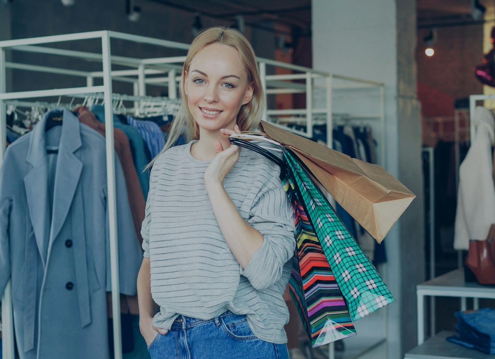 A smiling shopper carrying colorful shopping bags in a bright clothing store
